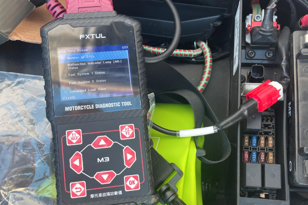 Piaggio Beverly scooter repair with diagnostic tool. A mechanic uses a tablet and multimeter to check the ECU and fix an engine warning light in a workshop.